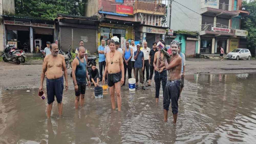 जगह-जगह गड्ढों से त्रस्त व्यापारी, पानी से भरे गड्ढों में नहा कर जताया विरोध